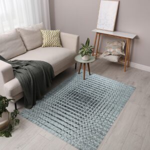 A light blue and dark grey grid-pattern rug lies under a beige sofa on light wood flooring.
