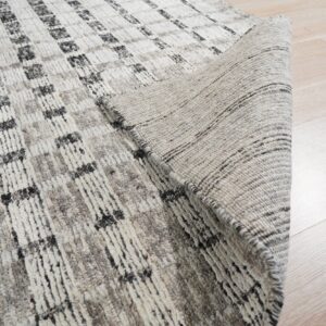 Textured gray and off-white rug with a grid pattern, showing the woven backing on light wood floor.