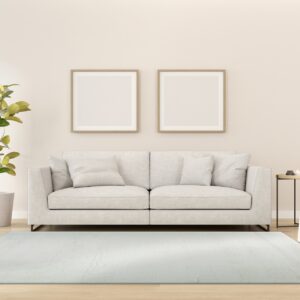 A light blue textured area rug anchors a minimalist room with a gray sofa and wood floor.