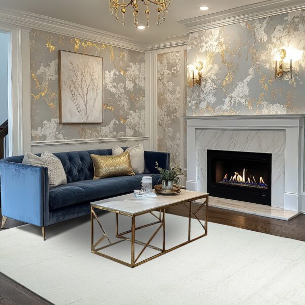 An off-white textured rug sits beneath a gold coffee table and navy blue tufted couch.