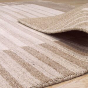 Beige and cream striped rug corner partially rolled back, showing medium pile on wood floor.