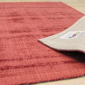 A coral textured rug with a linear grid pattern is folded back on light wood flooring.