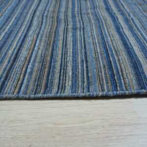 Low pile rug with thin vertical blue, tan, and gray stripes resting on pale wood floor.