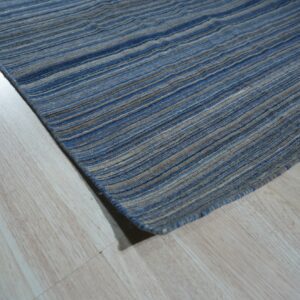 A blue and beige striped rug with a textured surface rests on light wood plank flooring.
