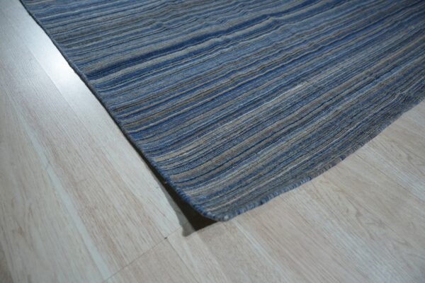 A blue and beige striped rug with a textured surface rests on light wood plank flooring.