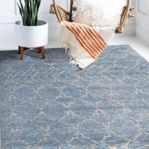 Low-pile blue trellis rug anchors a corner with a wicker chair, throw blanket, and snake plant.