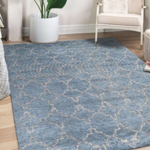 Blue ribbed rug with a beige geometric trellis pattern sits on wood flooring beside a white armchair.