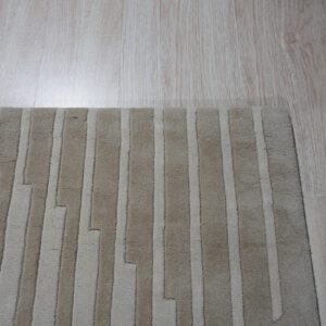 A textured beige rug with staggered vertical stripes sits on light wood flooring.