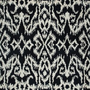 A close-up view of a black rug with an irregular, off-white, high-contrast ornamental pattern.