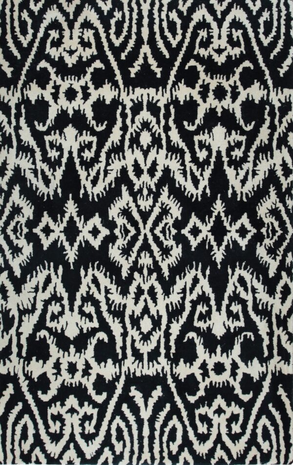 A close-up view of a black rug with an irregular, off-white, high-contrast ornamental pattern.