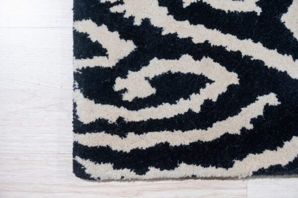 High-pile rug features black and cream wavy stripes placed over light wood flooring.
