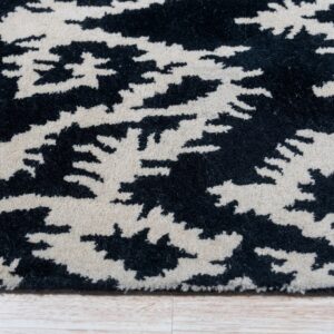 Close-up of a black and cream abstract patterned rug showing a textured pile resting on light wood flooring.