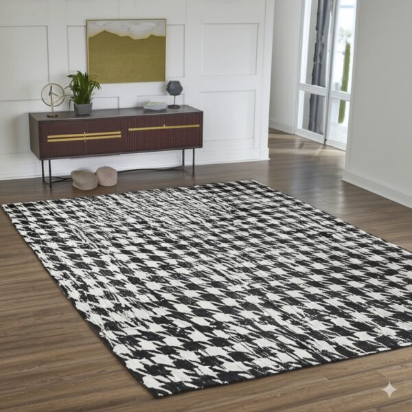 Black and white rug with a distressed houndstooth pattern lays on brown wood plank flooring.