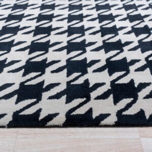 Black and cream high-pile rug with a houndstooth pattern rests on light wood plank flooring.