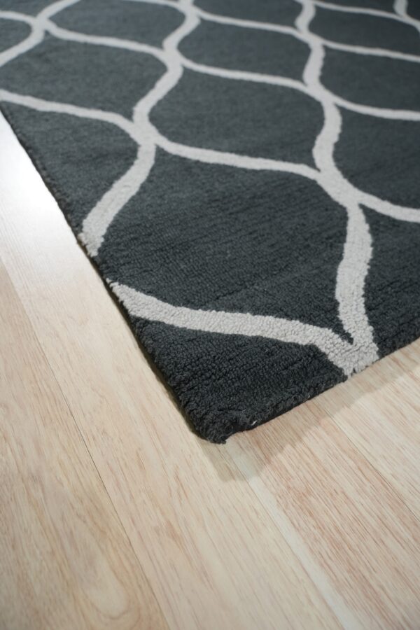 Close-up of a textured dark gray rug with a light ogee pattern on natural wood flooring.