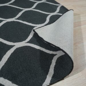 Dark textured rug with a gray trellis pattern showing its woven backing on a light wood floor.