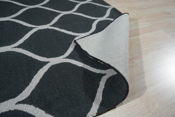 Dark textured rug with a gray trellis pattern showing its woven backing on a light wood floor.