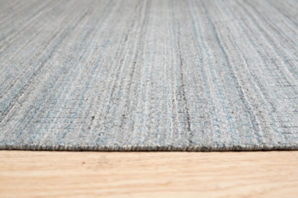 Textured gray rug with subtle blue vertical stripes rests on light wooden flooring.