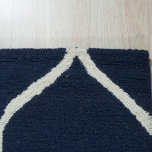 Textured navy blue rug with cream geometric lines lying on light wood flooring.