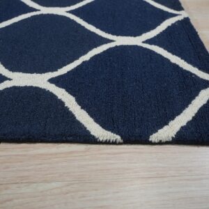 Navy blue rug with a textured white geometric pattern rests on light blonde flooring.