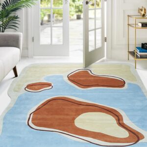 An abstract rug with blue, cream, and terracotta organic shapes lies on a white floor near French doors.