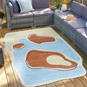 An irregularly shaped rug with blue, tan, and brown organic forms is on a sunny wooden outdoor deck.