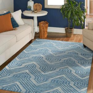 A blue and white geometric rug sits on hardwood floors in a living room with navy walls.