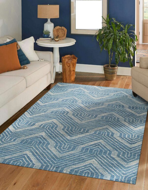 A blue and white geometric rug sits on hardwood floors in a living room with navy walls.