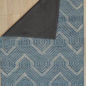 Blue and beige geometric rug on light wood floor, folded back to reveal the dark gray backing material.