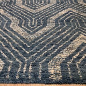 Distressed blue and cream high-pile rug featuring a geometric interlocking zigzag pattern on wood flooring.