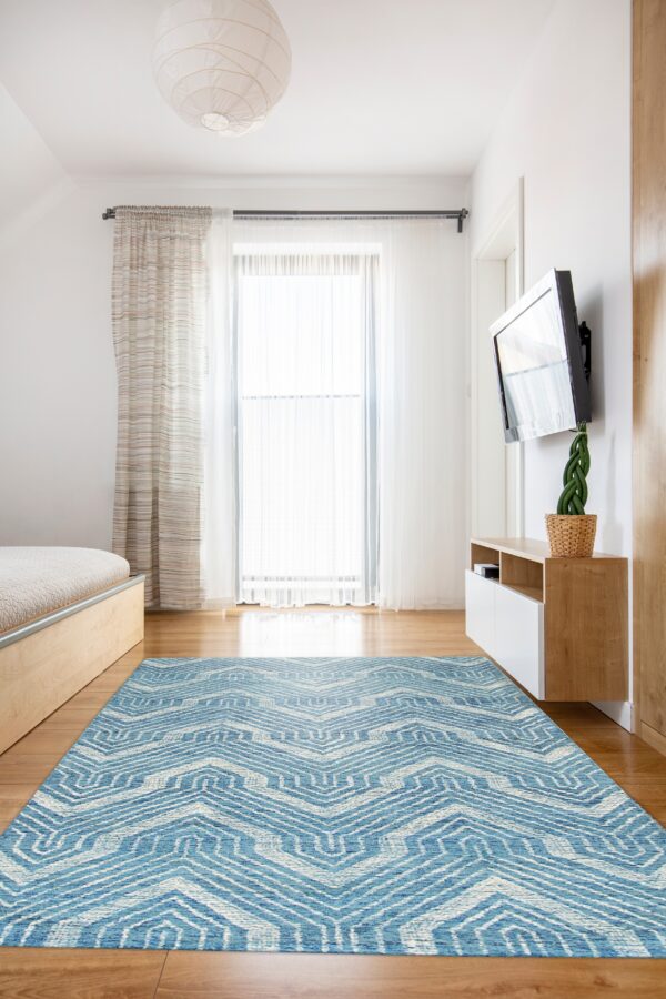 Blue and white rug featuring a detailed geometric chevron pattern covers wood flooring in a bright room.