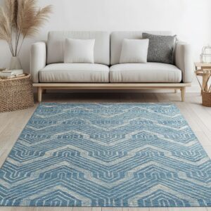 Blue and cream chevron rug centered on light wood floors beneath a white minimal sofa.