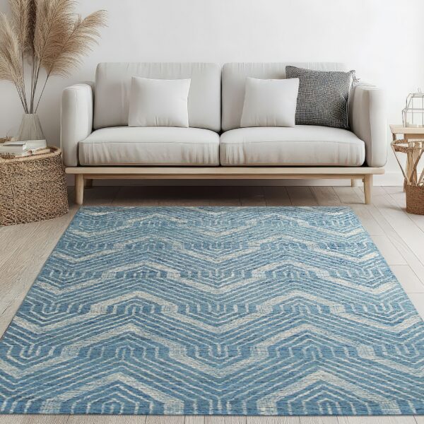 Blue and cream chevron rug centered on light wood floors beneath a white minimal sofa.