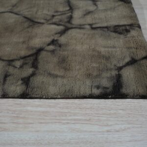 A taupe short-pile rug with a dark abstract cracked pattern rests on light wood flooring.