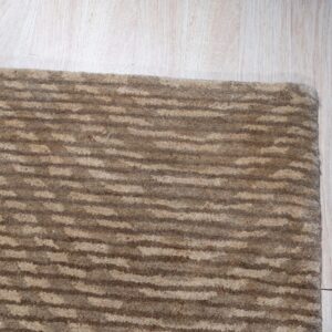 Close-up of a textured brown rug with horizontal stripe pattern on light wood plank flooring.