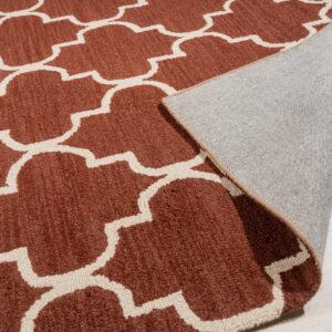Terracotta and cream high-pile rug featuring a quatrefoil pattern, lifted to show the backing on light wood flooring.