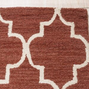High-pile rug in rust with a cream geometric pattern shown against light wood flooring.