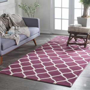 Plum and white ogee lattice rug on dark plank flooring beside a gray sofa.