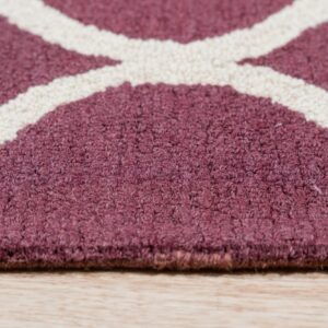Textured maroon rug with intersecting cream lines rests on light natural wood flooring.