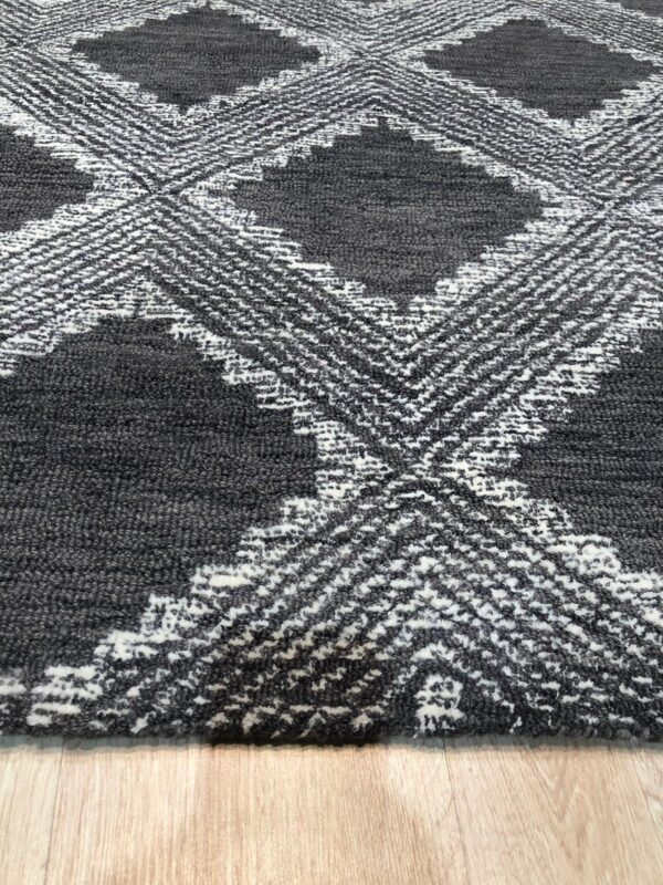 Textured dark gray rug featuring raised white diamond patterns resting on light wood flooring.