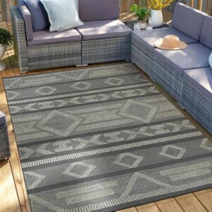 A grey and light geometric patterned rug anchors a sectional sofa on a wooden deck.