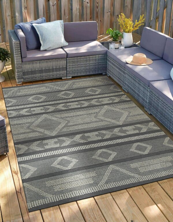 A grey and light geometric patterned rug anchors a sectional sofa on a wooden deck.