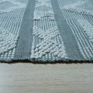 Textured gray rug with raised off-white diamond patterns and woven vertical stripes on light wood.