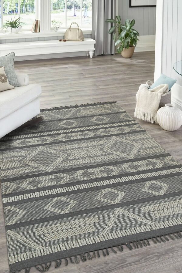 Low-pile charcoal and light gray geometric rug with tassel fringe sits in a bright living room.