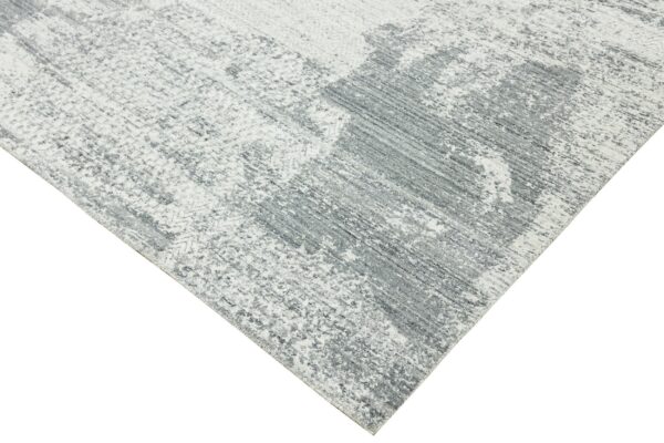 Gray and white rug with an abstract weathered design and mottled, textured low pile.
