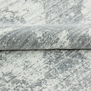 Abstract patterned high-pile rug folded, featuring shades of white and mottled gray.