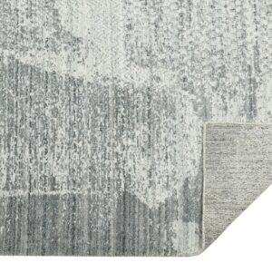 Abstract gray and white textured rug features distressed vertical lines; a corner is folded showing the woven backing.