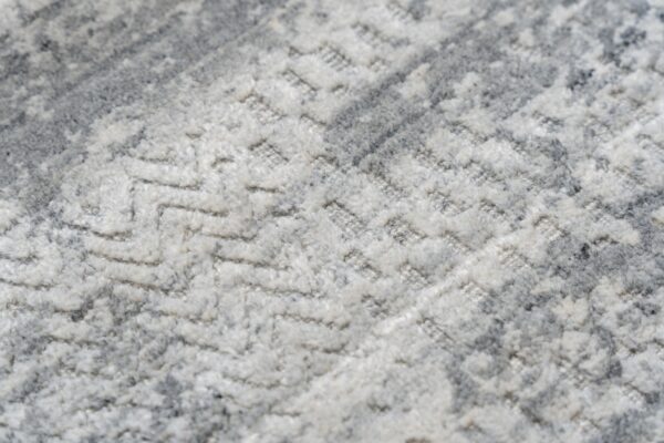 Gray and white high-pile rug detail showing a distressed abstract pattern and carved raised texture.