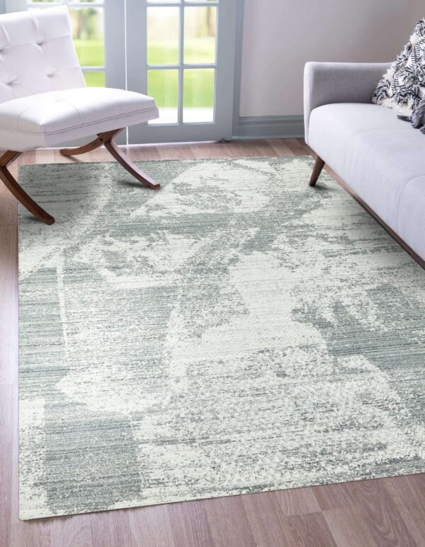 Light gray and white abstract rug on wood flooring between a white chair and gray sofa.