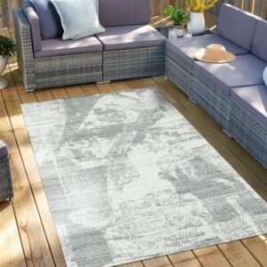 Abstract gray and white rug on a wooden deck surrounded by a large gray outdoor sectional.